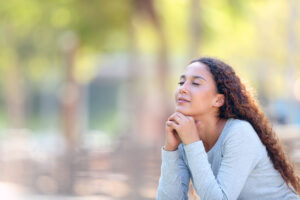 young worman sitting outside with her eyes closed