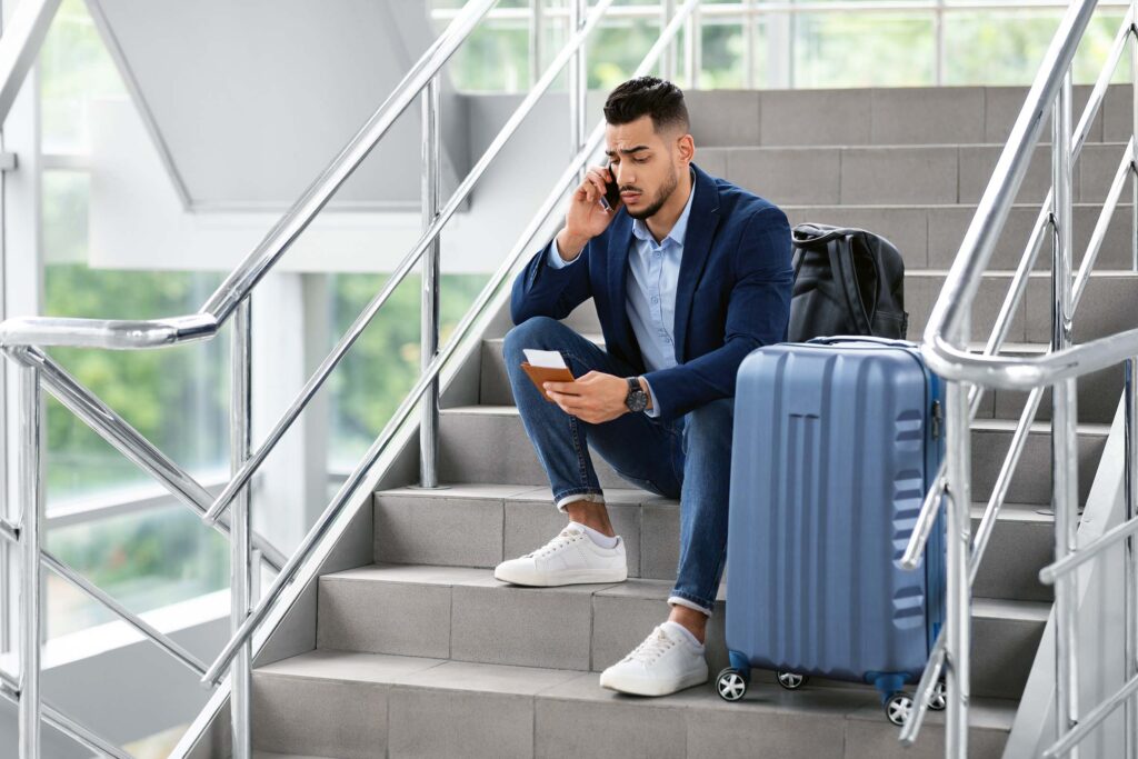 disgruntled traveler sitting on the steps and talking on his phone